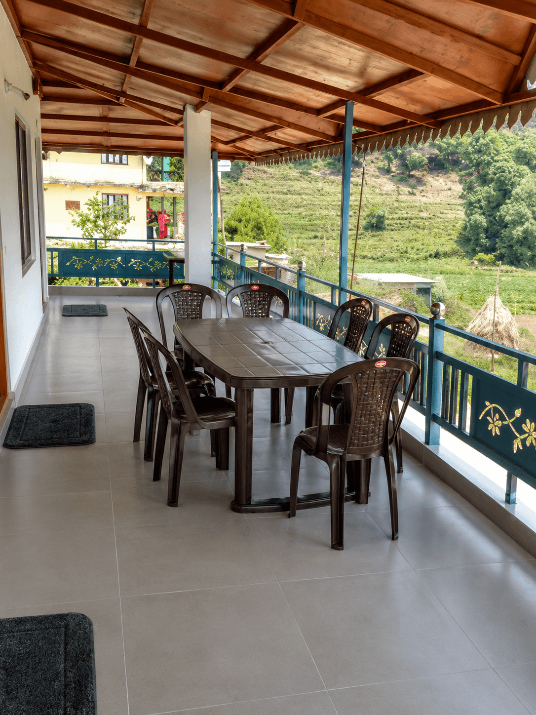Covered balcony seating area at Himgiri Home Stay with hillside greenery